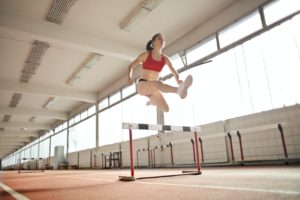 Running woman jumps over obstacle